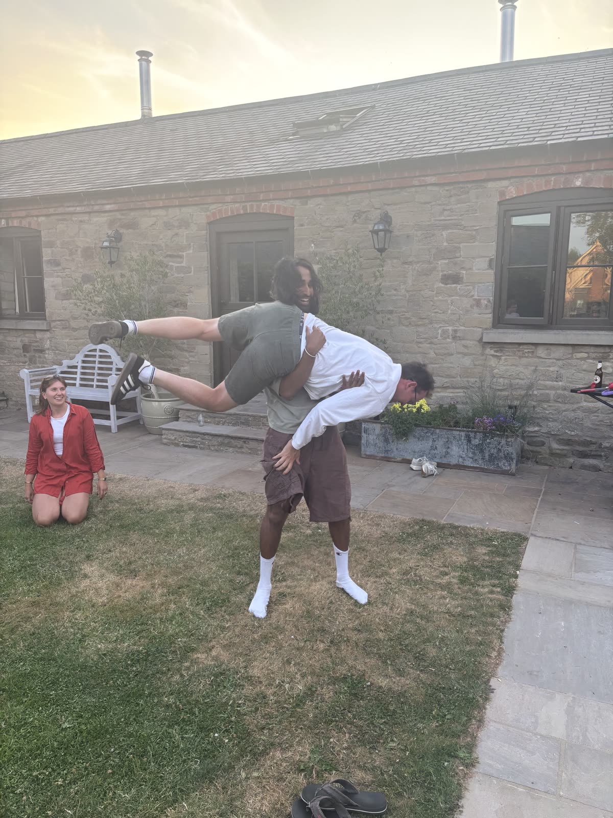 One of the team lifting a colleague over their shoulder while another laughs