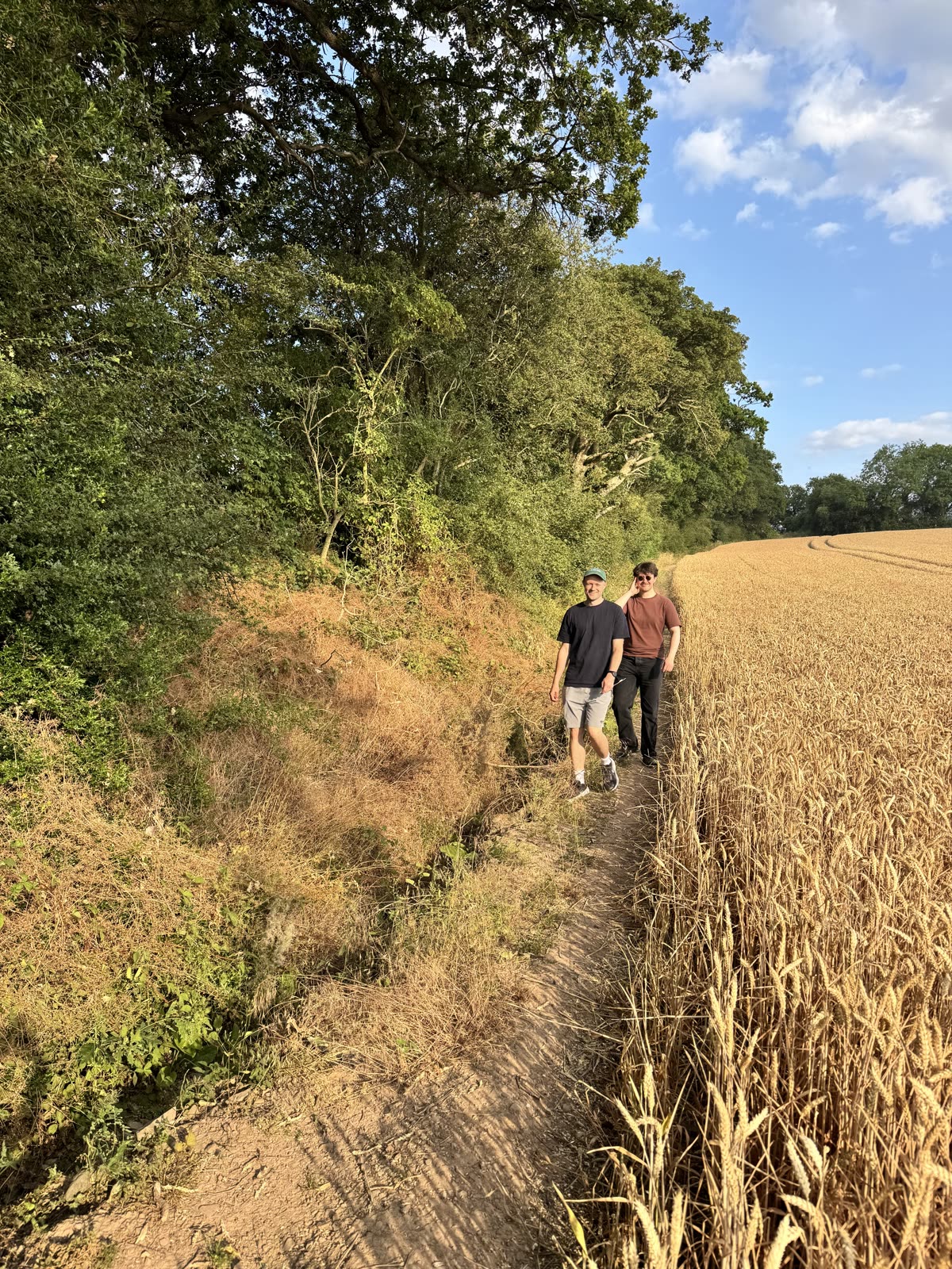 Two of the team walking a path beside a wheat field